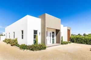 a white house with a driveway at Romantic Escape, Walk to Beach, Pool, Hammock in Long Bay Hills