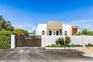 a house with a gate and a driveway at Romantic Escape, Walk to Beach, Pool, Hammock in Long Bay Hills