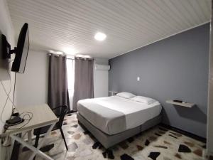 a bedroom with a bed and a desk and a television at Donde Emilio in Pereira