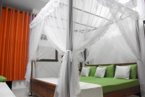 una camera con letto a baldacchino e cuscini verdi e bianchi di Meegahapokuna Resort a Anuradhapura