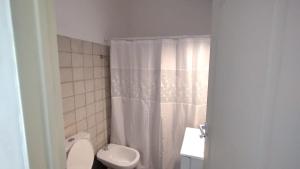 a bathroom with a white shower curtain and a toilet at Meular 2 Planta Baja in Pilar