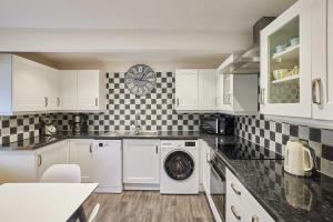 eine Küche mit weißen Schränken und einer Waschmaschine in der Unterkunft Host & Stay - Anvil Cottage in Kirkbymoorside