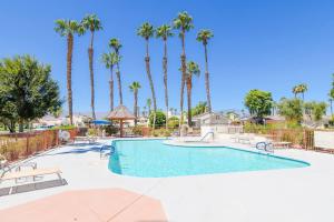 a swimming pool with palm trees in a resort at Desert Breezes Resort in Palm Desert