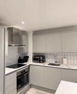 a white kitchen with white cabinets and a sink at Central Birmingham Luxury 2 Bedroom Apartment with Fast WiFi and Games Table in Birmingham