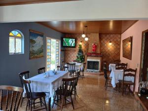 a dining room with tables and chairs and a fireplace at A Nossa Casinha no Bosque - 4min do Parque Capivari in Campos do Jordão