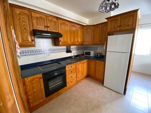 a kitchen with wooden cabinets and a white refrigerator at Atardecer Azul in Puerto Naos