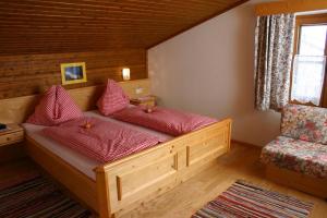 drewnianym łóżkiem z czerwonymi poduszkami w pokoju w obiekcie Berggasthof-Ferienbauernhof Habersatt w mieście Altenmarkt im Pongau