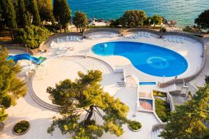 an overhead view of a large swimming pool next to the ocean at Hotel Dražica - Hotel Resort Dražica in Krk