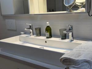 a bathroom sink with two faucets and a bottle of alcohol at Le Clos Marie in Fontaine-Milon