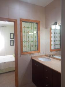 Un baño con lavabo, espejo y cama. en Villa Carmencita, en Pozo Alcón