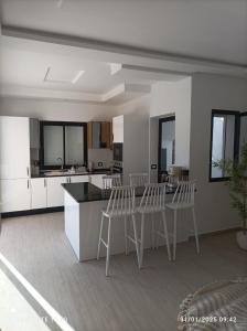 a kitchen with white cabinets and white stools at Villa Léann in Mezraya