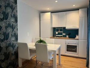 a kitchen with a white table and white chairs at La perle Lune in Ambérieu-en-Bugey