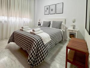 ein Schlafzimmer mit einem Bett mit einer karierten Decke in der Unterkunft Apartamento acogedor - piscina - parking in Sevilla