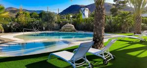 two chairs and a swimming pool with a fountain at Bellevall resort, hotel y apartamentos in Aspe