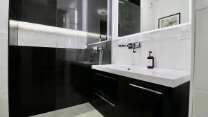a black and white bathroom with a sink and a mirror at Apartamenty Jurowiecka 13 in Białystok +27 photos