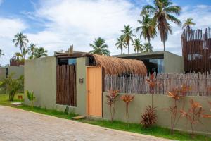 a house with a thatched roof and a fence at Paraíso Patacho Riviera Casa 01 Villa 04 in Pôrto de Pedras