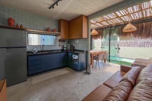 a kitchen with blue cabinets and a table with a couch at Paraíso Patacho Riviera Casa 01 Villa 04 in Pôrto de Pedras