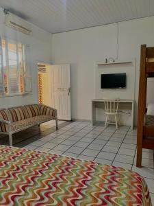 ein Zimmer mit einem Bett, einer Couch und einem Fernseher in der Unterkunft Floripa Hostel CENTRO in Florianópolis