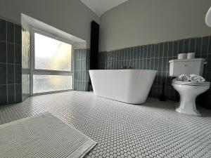 a bathroom with a tub and a toilet and a window at The Round House in Strangford +16 photos