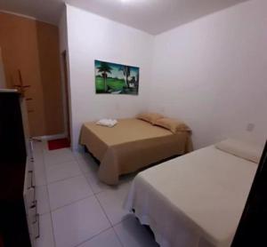 a bedroom with two beds and a picture on the wall at Casa de Praia na rota de Milagres - Praia de Marceneiro in Passo de Camarajibe