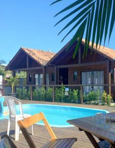 Una piscina con sillas y una mesa y una casa. en POUSADA ROSA e POESIA, en Praia do Rosa