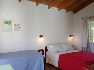 two beds in a room with white walls and wooden ceilings at Cabañas Club del Lago in La Falda +68 photos