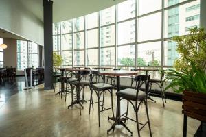 a restaurant with tables and chairs and large windows at Piemonte Hotel in Nova Lima