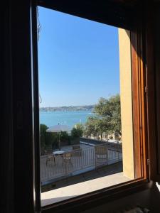 ein Fenster mit Blick auf den Balkon mit Blick auf das Wasser in der Unterkunft Appartamento Vista Lago! in Gardone Riviera