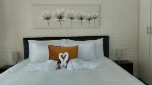a bed with white pillows and a pair of white scissors at The Berna in Cape Town