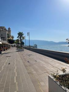 einen leeren Bürgersteig am Meer mit Palmen in der Unterkunft Appartamento Vista Lago! in Gardone Riviera