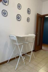 einen weißen Tisch und Stuhl in einem Zimmer mit Platten an der Wand in der Unterkunft Appartamento Vista Lago! in Gardone Riviera + 21 Fotos