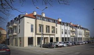 a large white building with cars parked in a parking lot at Apartament Nova Starówka in Konin