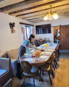 a woman is sitting at a long table at Pensiunea Bradet in Broşteni
