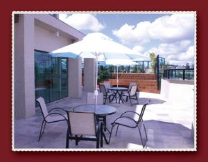 een patio met tafels en stoelen en een parasol bij Master Plaza Hotel in Barbacena