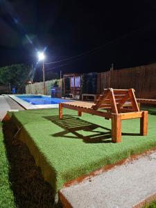 a wooden bench sitting next to a pool at night at Complejo Huayra Huasi in Villa Bustos