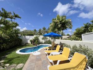 a patio with yellow chairs and a swimming pool at Villa Tamarind in Saint Peter