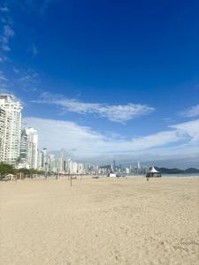 una playa de arena con una ciudad en el fondo en Turim, en Balneário Camboriú