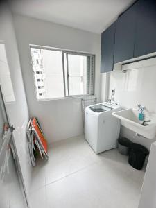 Un baño blanco con lavabo y lavadora. en Turim, en Balneário Camboriú