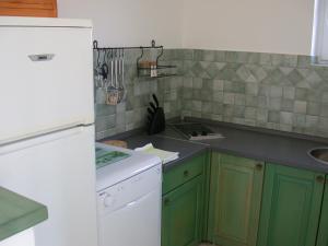 a kitchen with green cabinets and a white refrigerator at Vis a Vis Apartments in Baška