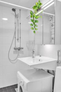 une salle de bain blanche avec un lavabo et un miroir dans l'établissement Design District w Free Parking Garage, Balcony, Netflix, 200m tram&bus, à Helsinki