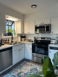 a kitchen with white cabinets and a stove top oven at Lovely 2BR Condo near UNCW Beach in Wilmington