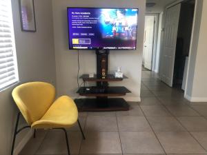サラソタにあるStylish Nordic Stay, Walk To Hospital & Beachesの黄色い椅子2脚、壁に薄型テレビが備わります。
