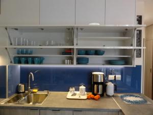 Una cocina con gabinetes azules y blancos y un fregadero. en Apartament Przy Plaży, en Krynica Morska 19 fotos más