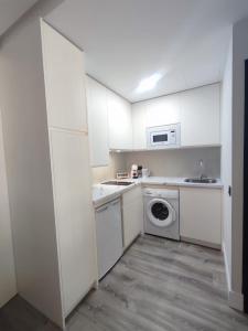 a kitchen with white cabinets and a washer and dryer at Casa de las Brasas - Piso frente al Palacio Real de Aranjuez in Aranjuez