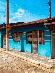 un bâtiment bleu avec des fenêtres à barreaux dans une rue dans l'établissement Casa & Hospedagem Carol, à Cachoeira Paulista