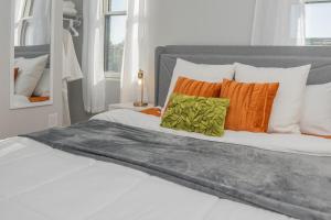 ein weißes Bett mit orangefarbenen und grünen Kissen darauf in der Unterkunft Sleep like a King - OTR- Free Light Rail ! in Cincinnati