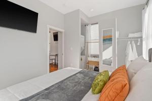 ein weißes Schlafzimmer mit einem großen Bett und einem orangefarbenen Kissen in der Unterkunft Sleep like a King - OTR- Free Light Rail ! in Cincinnati