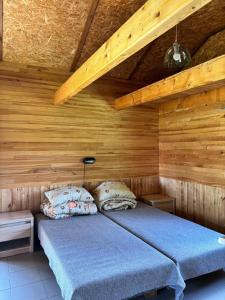 a bedroom with a bed in a wooden cabin at Kempings Paegļi in Kaijciems +4 photos