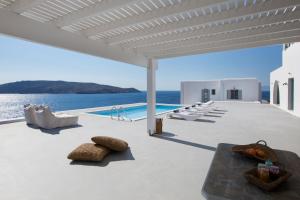 un patio con sedie, una piscina e l'oceano di CasaDei Pool 4-BDR Sea View Villas 'Anemos' & 'Petra' with Nighttime Security Guard a Panormos - Mykonos