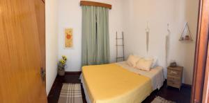 a small bedroom with a yellow bed and a window at Descanso imparcial in Prazeres